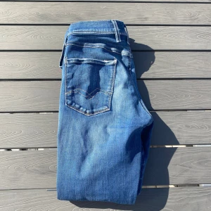 Blå jeans från Replay - Snygga blå jeans från Replay med klassisk femficksdesign och knappgylf. Perfekta för en avslappnad stil. De har en lätt tvättad look som ger en cool och trendig känsla.