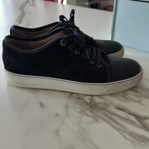 Svarta/mörkblåa sneakers från Lanvin - Jag beställde dem här Snygga svarta sneakers från Lanvin i mocka från careofcarl som jag beställde för ungefär 4500 i sommars nu har jag vuxit ur dem och nu vill jag ha ett par andra skor TAR EJ BYTEN med snörning och rund tå. Perfekta för en stilren look med en vit sula som ger en fräsch kontrast. Passar bra till både jeans och linnebrallor