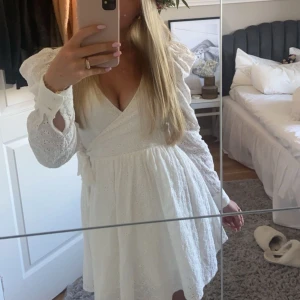 Vit omlottklänning från NA-KD - Säljer en söt vit omlottklänning från NA-KD med v-ringning och knytband i midjan. Den är i storlek 34 och perfekt för student, skolavslutning eller som en sommarklänning😍😍