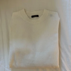 Vit stickad tröja från Massimo Dutti - Säljer en stilren vit stickad tröja från Massimo Dutti. Tröjan har en rund halsringning och ribbade muddar vid ärmslut och nederkant. Perfekt för en klassisk och tidlös look.                      