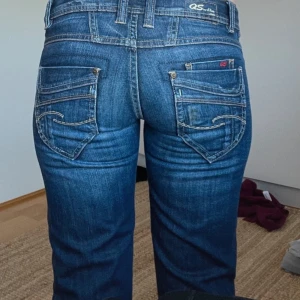 Blå jeans från QS by S.Oliver - Snygga blå jeans från QS by S.Oliver med klassisk femficksdesign och dekorativa sömmar på bakfickorna. Jeansen har en normal passform . De har en knappgylf och bälteshällor för extra stil och funktion. Innerbenslängden:83cm.  Midja:36cm storlek W34 och L34