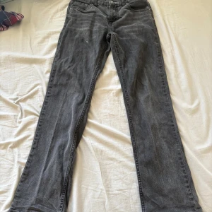 Grå Levis 551Z jeans - Säljer ett par grå Levis 551Z jeans med straight passform. Klassisk design med fem fickor och knappgylf. Perfekta för en avslappnad stil. Utsvängda jeans(man ser inte på bilden) Jätte många defekter. Ett litet hål där bak, spilt lite färg där framme och kanske lite fler men har inte upptäckt de än😁Säljer billigt