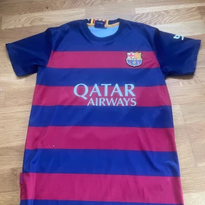 Blåröd FC Barcelona fotbollströja - Säljer en blåröd randig FC Barcelona fotbollströja med Neymar Jr och nummer 11 på ryggen. Tröjan har korta ärmar och Qatar Airways som sponsorlogga på framsidan. Perfekt för fotbollsfans!
