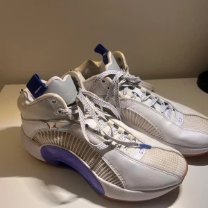 Basketskor Air Jordan XXXV - Snygga vita sneakers med blå detaljer från Nike. Skorna har snörning och en rund tå. Perfekta för en sportig look med en stilren design.
