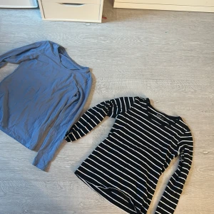 Två långärmade tröjor från ullared - Säljer en svart och vit randig långärmad tröja från Basic. Tillverkad i ekologisk bomull för en skön och hållbar känsla. Perfekt för en avslappnad stil.