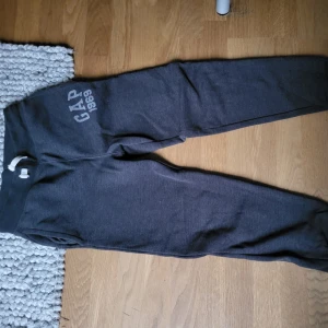 Mörkgrå mjukisbyxor från GAP - Säljer ett par mörkgrå mjukisbyxor från GAP med tryck 'GAP 1969' på sidan. Byxorna har en otroligt bekväm passform och är perfekta för allt från hemmamys till träning. Använda ett fåtal gånger men inga defekter. Priset är diskuterbart, så kontakta gärna!