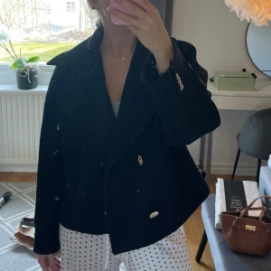 Marinblå kappa med guldknappar - Snygg marinblå kappa med guldknappar. Perfekt för en stilren look. Kappan har en klassisk design med långa ärmar och en elegant passform.