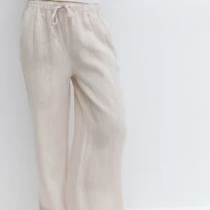 Beige linnebyxor med dragsko - Snygga och bekväma beige linnebyxor med elastisk midja och dragsko. Perfekta för en avslappnad stil med en loose passform och vida ben.