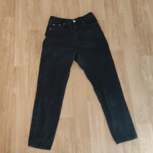 Svarta jeans från Gina Tricot  - Snygga svarta högmidjade jeans från Gina Tricot i storlek 36. Klassisk design med fem fickor och knappar i silverfärg. Lätt urtvättad design. Perfekta för en stilren look.