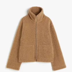 Beige teddyjacka med dragkedja - Mysig beige teddyjacka med dragkedja framtill och hög krage. Perfekt för kyliga dagar med sin fluffiga och varma design. Jackan har två stora fickor framtill för extra komfort och stil.