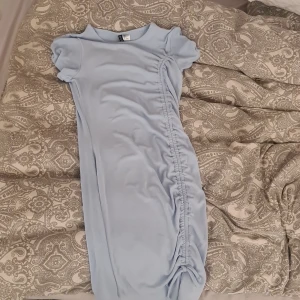 Ljusblå ribbad klänning från H&M Divided - Supersöt ljusblå ribbad klänning från H&M Divided med korta ärmar och snygg rynkdetalj längs sidan som avslutas med en knytning. Perfekt för dig som gillar en enkel men trendig look.🎀