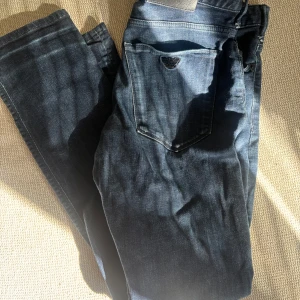 Mörkblå jeans från Armani - Säljer ett par klassiska mörkblå jeans från Armani med fem fickor och diskret logga på bakfickan. Jeansen har normal passform och raka ben, perfekta till vardags. Snygga detaljer och robust denimkänsla.