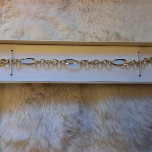 Armband i 18k vitt och gult guld - Elegant armband med länkar i både gult och vitt guld. Armbandet har ett klassiskt karbinlås och dekorativa, tvinnade länkar som ger ett exklusivt intryck. 20 cm och cirka 4.5 g