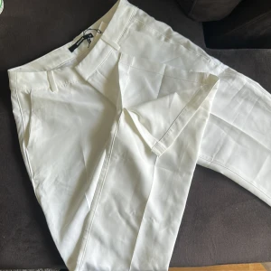 Vita kostymbyxor från Bik Bok - Snygga vita kostymbyxor från Bik Bok med klassisk passform. Byxorna har dragkedja och knapp framtill samt två ”fejk fickor” bak. Perfekta för en stilren look och passar till många olika outfits. Nypris 400kr.