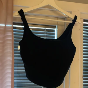 Svart croppad linnetopp från Gina Tricot - Säljer en svart croppad linnetopp från Gina Tricot. Toppen har breda axelband och rundad halsringning. Perfekt att matcha med jeans eller kjol för en enkel och stilren look.