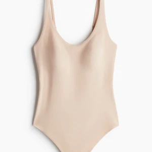 Beige body och shapewear - Stilren beige body/shapewear med smala, justerbara axelband och rundad urringning. Tillverkad i ett mjukt, stretchigt material och har tryckknappar i grenen för enkel av- och påtagning. Den är helt ny bara testad.