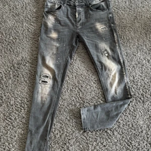 Grå slitna jeans från Alessandro Zavetti - Säljer ett par grå jeans från Alessandro Zavetti med slitna detaljer och ljusa partier. Byxorna har fem fickor, dragkedjegylf och en smal passform. Perfekta inför sommaren. pris kan diskuteras