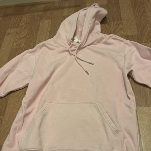 Ljusrosa hoodie med ficka, Hm - Mysig ljusrosa hoodie med stor ficka framtill och justerbar huva. Perfekt för chill dagar eller när du vill vara extra bekväm. Klassisk modell med långa ärmar och mjukt material.