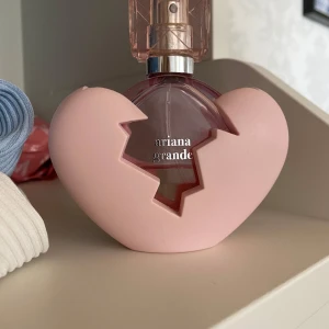 Ariana Grande parfym i hjärtformad flaska - Säljer en Ariana Grande parfym i en unik hjärtformad flaska med rosa detaljer. Flaskan har en trasigt hjärta-design och är tillverkad i glas och plast. Parfymen rymmer 30 ml och har en elegant, feminin look med genomskinlig rosa färg. Ca 15 ml kvar. Säljer pga att doften inte passar mig. 