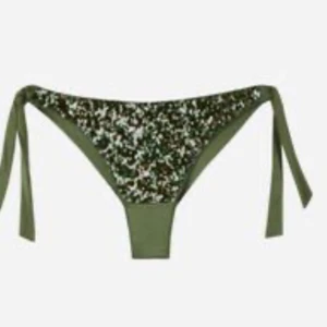 Grön Calzedonia bikini med paljetter och knyt - Snygg olivgrön bikini med glittriga paljetter på både överdel och underdel. Både toppen och trosan har knytband i sidorna och nacken för justerbar passform. Säljs inte längre o väldigt trendig! Använd fåtal ggr och säljer pga att den är för stor.
