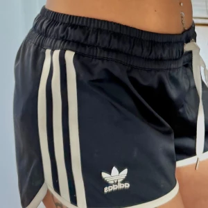 Glansiga y2k adidas shorts - Ena snöret är skadat annars inga andra anmärkningar eller tecken på användning  Dom är marin blå  (Spegeln som är smutsig på bild nr 2, inte shortsen)