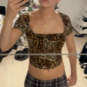 Leopardmönstrad croppad topp - Säljer en croppad topp med leopardmönster och korta ärmar. Toppen har en fyrkantig urringning och sitter tight. Perfekt för dig som vill sticka ut med ett djurmönster. Vet tyvärr inte vart den är från men köpte från second hand.