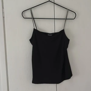 Svart topp med glittriga axelband   - Säljer en svart linnetopp från Pieces med glittriga axelband. Toppen passar perfekt till sommaren och är endast använd ett fåtal gånger.
