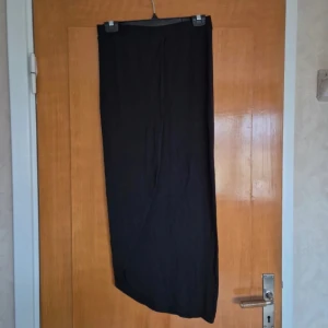 Svart lång kjol med slit str S - Svart lång kjol i glansigt material storlek S Slit med på ena sidan. Aldrig använd  Alla kläder rollas innan dom skickas då katt finns i hemmet!  #svartkjol #blackskirt #långkjol #wilmabookss #wilmabooksstorleks