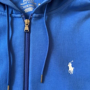 Blå Zip hoodie från Polo Ralph Lauren - Säljer denna feta Zip Hoodien från Ralph Lauren i storlek S. Den är i bra skick inte använd så mycket och passar perfekt till sommaren som snart är här. Om ni är intresserade hör gärna av er. Har även en grå på min sida så om man är intresserad av båda så ska vi kunna lösa ett bättre pris.