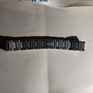Silverfärgad länkarmband från Lacoste - Säljer ett silverfärgat länkarmband från Lacoste med klassisk krokodil-logga på mittenlänken. Armbandet har en stilren design med texturerade detaljer på länkarna. Perfekt som utbytbar länk till din Lacoste-klocka. Oanvänd