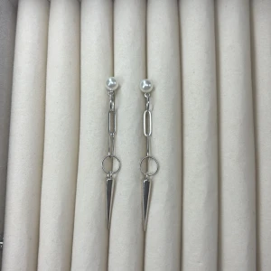 Långa silverfärgade örhängen med pärldetalj - Säljer ett par trendiga örhängen i silverfärg med små vita pärlor upptill och spetsiga hängen. Kedjedetaljer och cirklar ger ett modernt uttryck. Perfekta för dig som gillar statement-smycken.