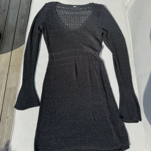 Svart stickad klänning med v-ringning från BikBok - Svart stickad klänning från BikBok med v-ringning och långärmade trumpetärmar. Klänningen har ett fint hålmönster upptill och vid ärmarna, samt markerad midja. Storlek M men är större i storlek. 