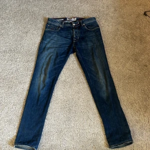 Blå limited edition jeans från Jacob Cohen - Säljer ett par blå jeans från Jacob Cohen, limited edition (276 av 841). Klassisk femficksmodell med raka ben och knappar framtill. Snygga röda sömmar och detaljer. Storlek 33 och är  47cm bred vid medjan och benlängden är 104 cm