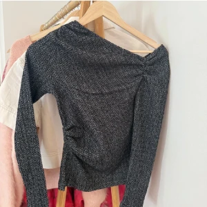 Mörkgrå ribbad offshoulder tröja - Säljer en mörkgrå ribbad tröja med offshoulder-design. Tröjan har lång ärm och är figurnära i modellen. Perfekt för dig som vill ha en stilren och trendig topp till garderoben.