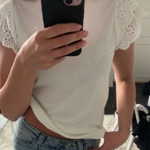 Vit topp med volangärmar från SHEIN - Supersöt vit topp från SHEIN med broderade volangärmar. Toppen är ribbad och har en rund halsringning. Perfekt att styla med jeans eller kjol.