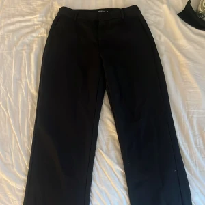 kostymbyxor  - Säljer ett par klassiska svarta kostymbyxor från Gina Tricot. Byxorna har normal passform, raka ben och hällor för bälte. Perfekta för en stilren look och passar till många olika outfits.