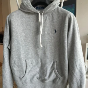Grå hoodie från Polo Ralph Lauren - Säljer en klassisk grå hoodie från Polo Ralph Lauren i mycket bra skick. Storlek M men passar S