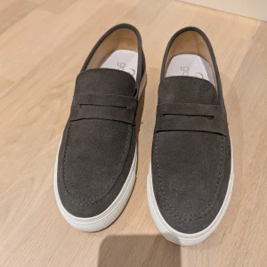 Mörkgrå mocka loafers med vit sula i stl 42 - Stilrena mörkgrå loafers i mocka från Goosecraft med vit platt sula. Skorna har rund tå och klassisk design utan snörning, perfekta för en clean look.