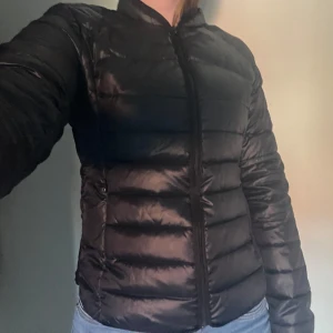 Svart pufferjacka från Filippa K - Säljer en svart pufferjacka från Filippa K i storlek L. Jackan har lång ärm, dragkedja framtill och klassisk ståkrage. Perfekt för kyligare dagar och enkel att matcha med olika outfits. Oanvänd.