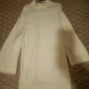 Vit stickad polotröja - Mysig vit stickad polotröja med lång ärm och hög krage. Tröjan är lite längre i modellen och har en klassisk, enkel design som passar perfekt till kyligare dagar.