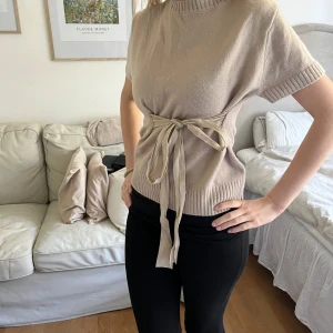 Beige stickad topp med knytband - Säljer en beige stickad topp med korta ärmar och rosett från Zara. Storlek m