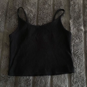 Svart ribbad linnetopp - Säljer en svart croppad ribbad linnetopp med smala axelband. Använt Max 2 gånger, köpt på NewYorker och säljer den för endast 10kr. Vid frågor är det bara att kontakta💕