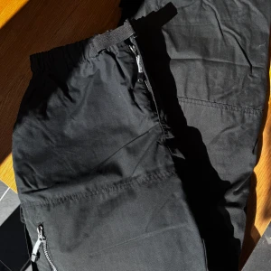 Svarta friluftsbyxor  - Svarta friluftsbyxor med elastisk midja och dragkedjor på fickorna. Materialet är slitstarkt och de har flera praktiska fickor. Rensar ur min garderob från en hel del oanvända kläder🌼 Om du ser något mer i min profil som du gillar så skickar jag med det till dig också!😊 Fler kläder kommer! 
