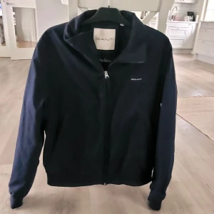 Mörkblå jacka från GANT med dragkedja - Säljer en mörkblå jacka från GANT som är lättfodrad och är i fint skick 