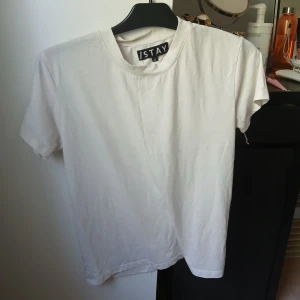 Vit t-shirt från ISTAY - En klassisk vit t-shirt från ISTAY i mjuk bomull. T-shirten har rund halsringning och korta ärmar, perfekt för en enkel och clean look. Passformen är normal och materialet känns skönt mot huden.