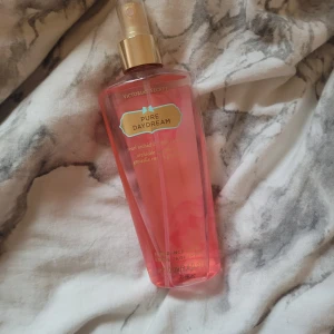 Victoria's Secret Pure Daydream Body Mist - Fräsch och söt body mist från Victoria's Secret i doften Pure Daydream. Flaskan är genomskinlig med rosa vätska och har en guldfärgad spraykork. Doften innehåller noter av päron och orkidé.