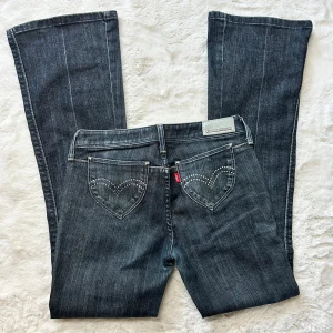 Lågmidjade bootcut jeans Levis vintage  - Supersnygga och ovanliga jeqns från Levis med super coola fickor med stenar på. Storlek w26 L32 enligt lapp. Passar även mig som brukar ha 27. (Se mått) innerbenslängd:78 midjemått:36-37. Obs finns ett pyttepytte litet ”skav” i skrevet. Absolut inget man ser eller tänker på vid användning.Kan skicka bild privat. Köp sker via köp nu, jag postar inom 24h. Kvar tills markerad såld 