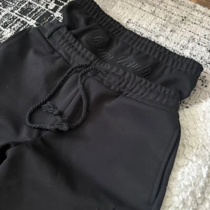 Svarta mjukisbyxor från Forum Vondix - Svarta mjukisbyxor med broderad logga på benet och bakfickan. Byxorna har resår i midjan med dragsko och raka ben. Perfekta för en avslappnad stil och har snygga detaljer som stjärna framtill.