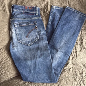 Blå jeansbyxor från Dondup - Snygga blå jeansbyxor från Dondup med klassisk femficksdesign och orange kontrastsömmar. Byxorna har normal passform och raka ben. Perfekta för dig! Modell George storlek 31. Slim fit.