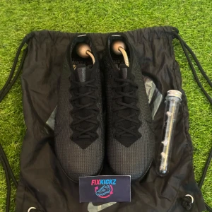 Nike Mercurial - Säljer ett par svarta Nike Mercurial fotbollsskor med snörning och rund tå. Skorna har en ovandel i syntetmaterial och fasta dobbar för spel på gräs. Snygg, diskret Nike-logga på sidan och klassisk design.